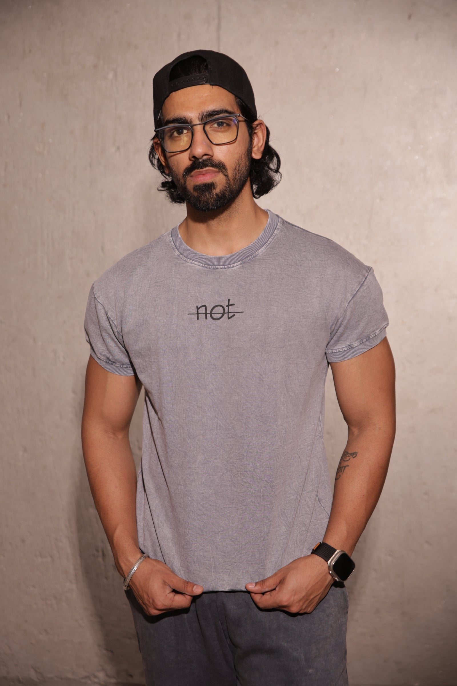Man wearing a gray t-shirt with a logo, standing against a plain background