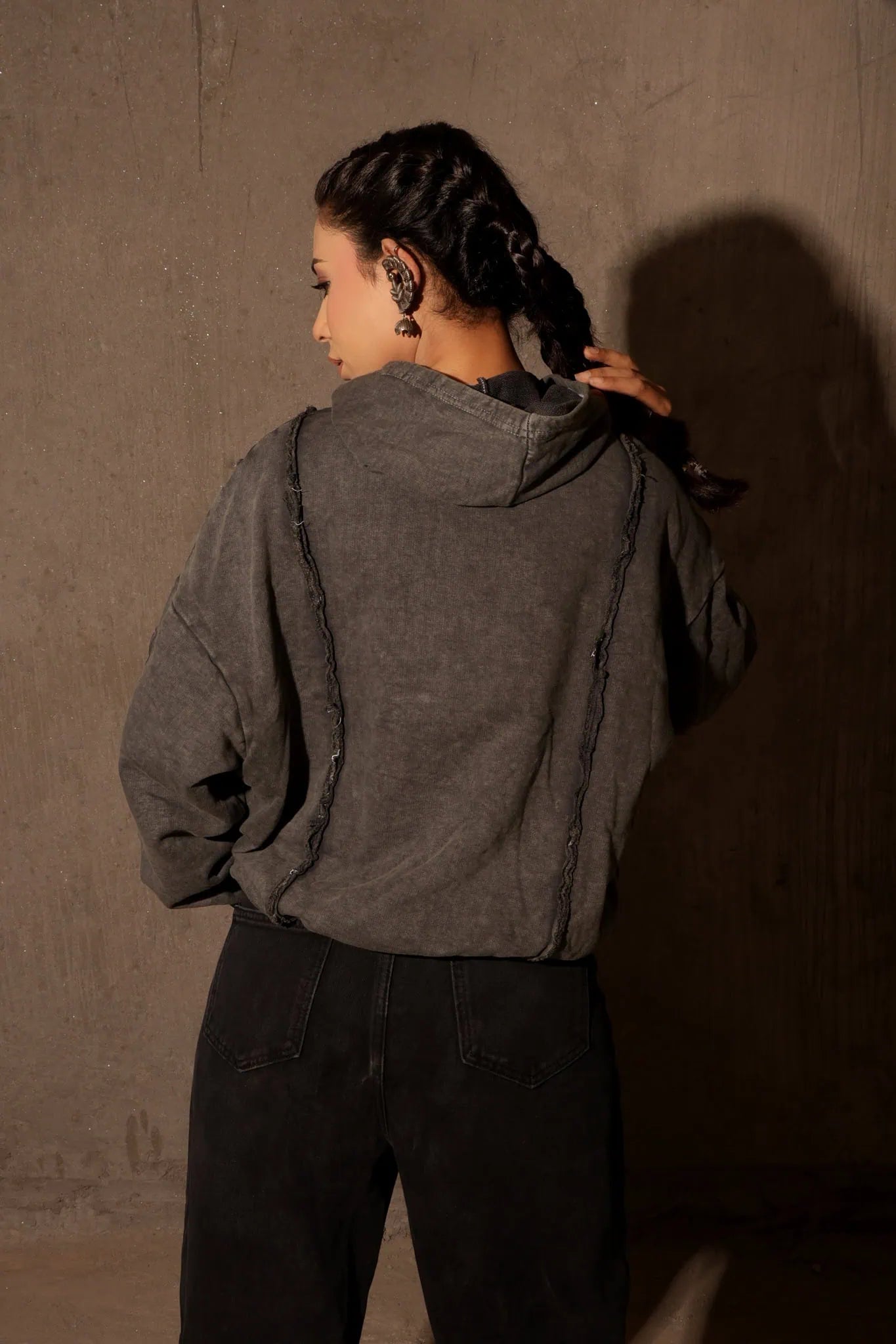 Person wearing a dark gray jacket against a plain wall