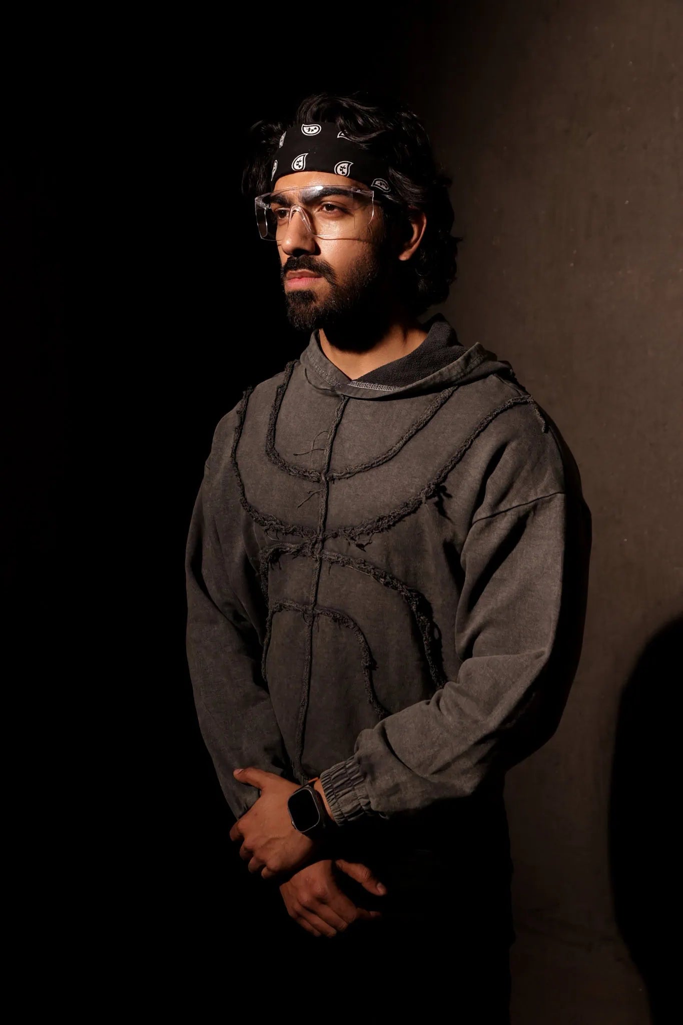 Man wearing a dark hoodie and headband against a plain background