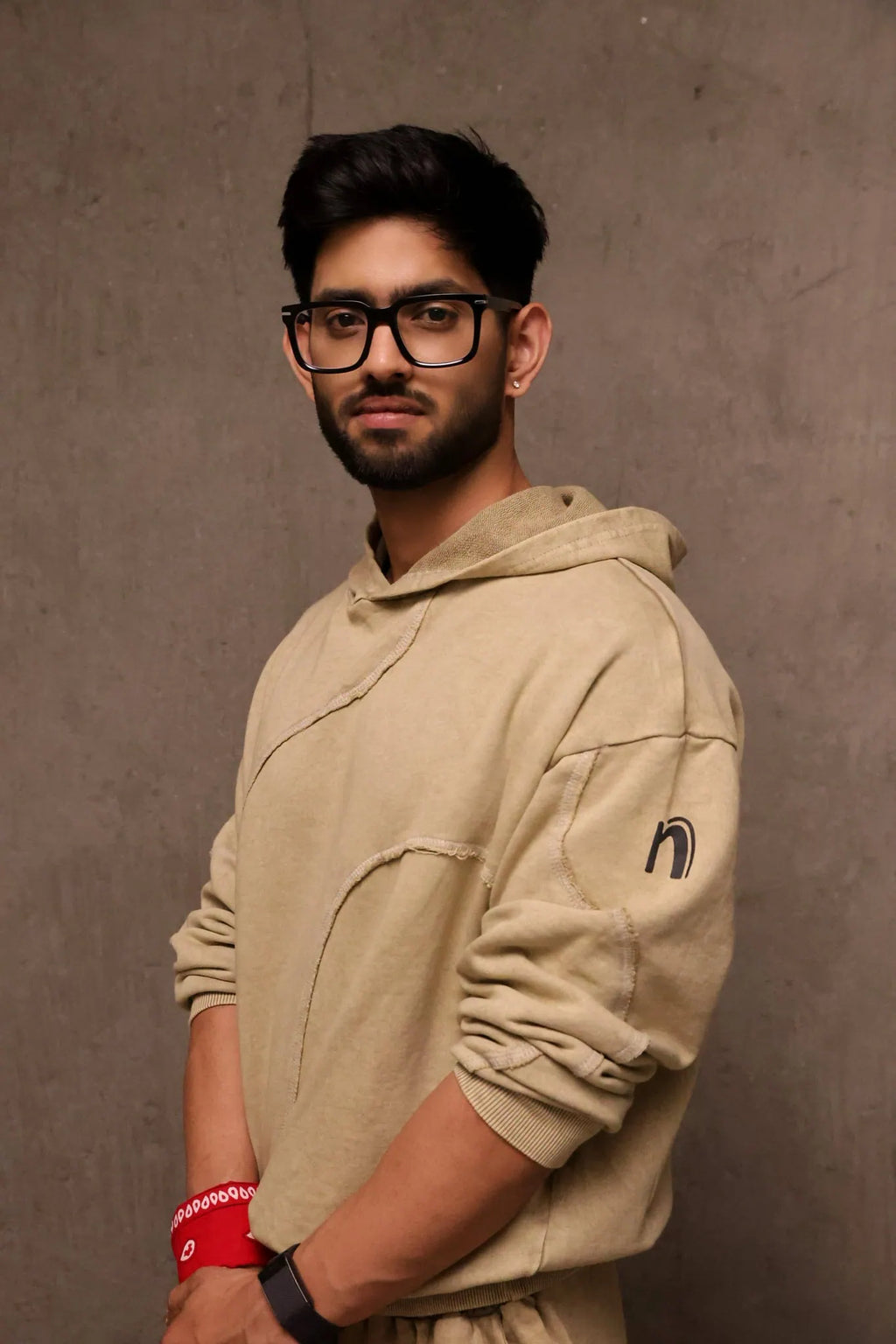 Man wearing a beige hoodie with a logo on a brown background