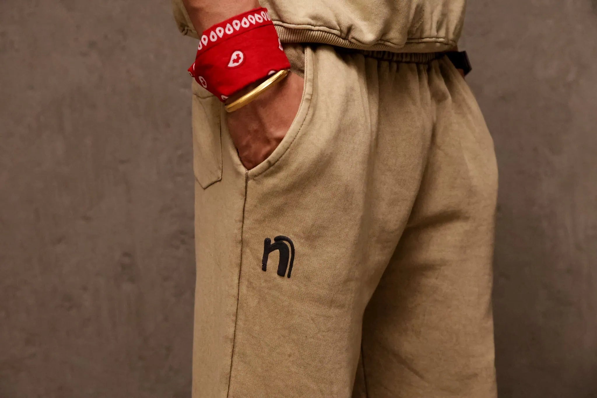Person wearing beige pants with a logo and red boxing glove on a brown background