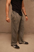 Person wearing gray pants and black shoes against a beige wall.