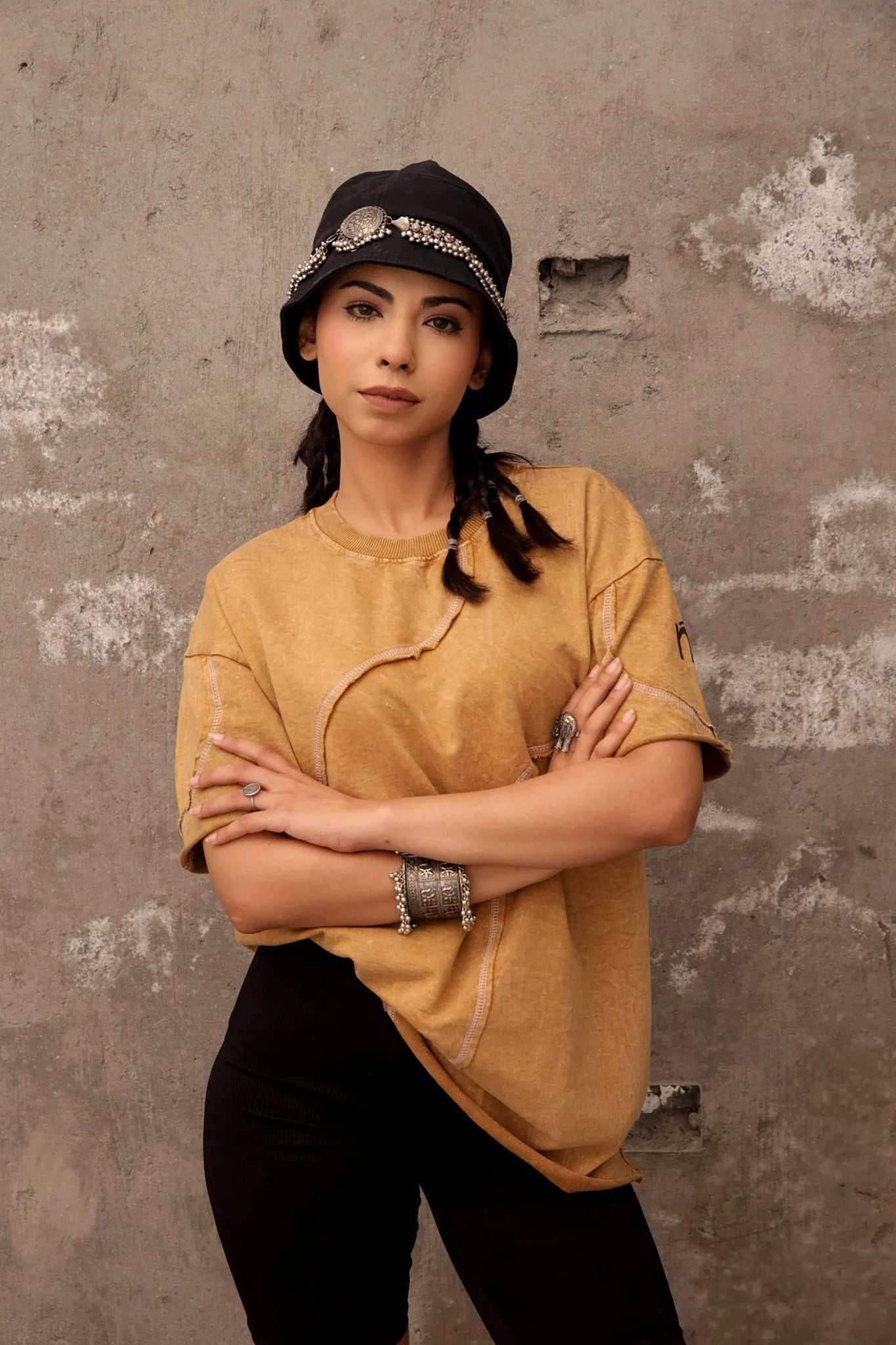 Person wearing a yellow shirt and black cap against a textured wall