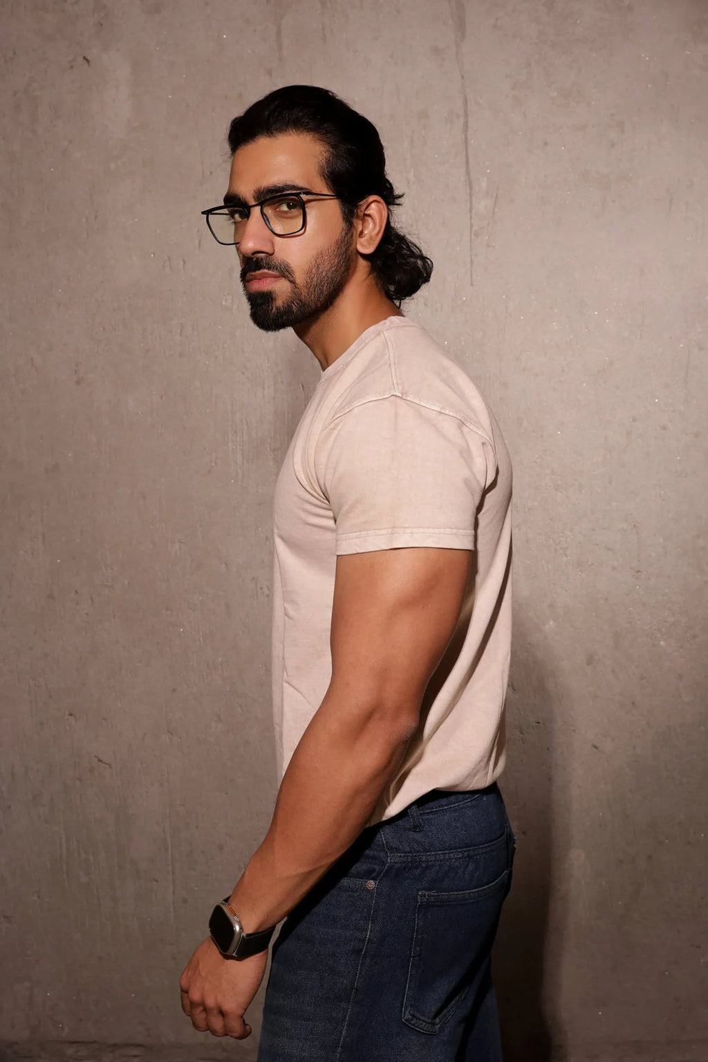 Man wearing glasses and a light-colored t-shirt against a plain background