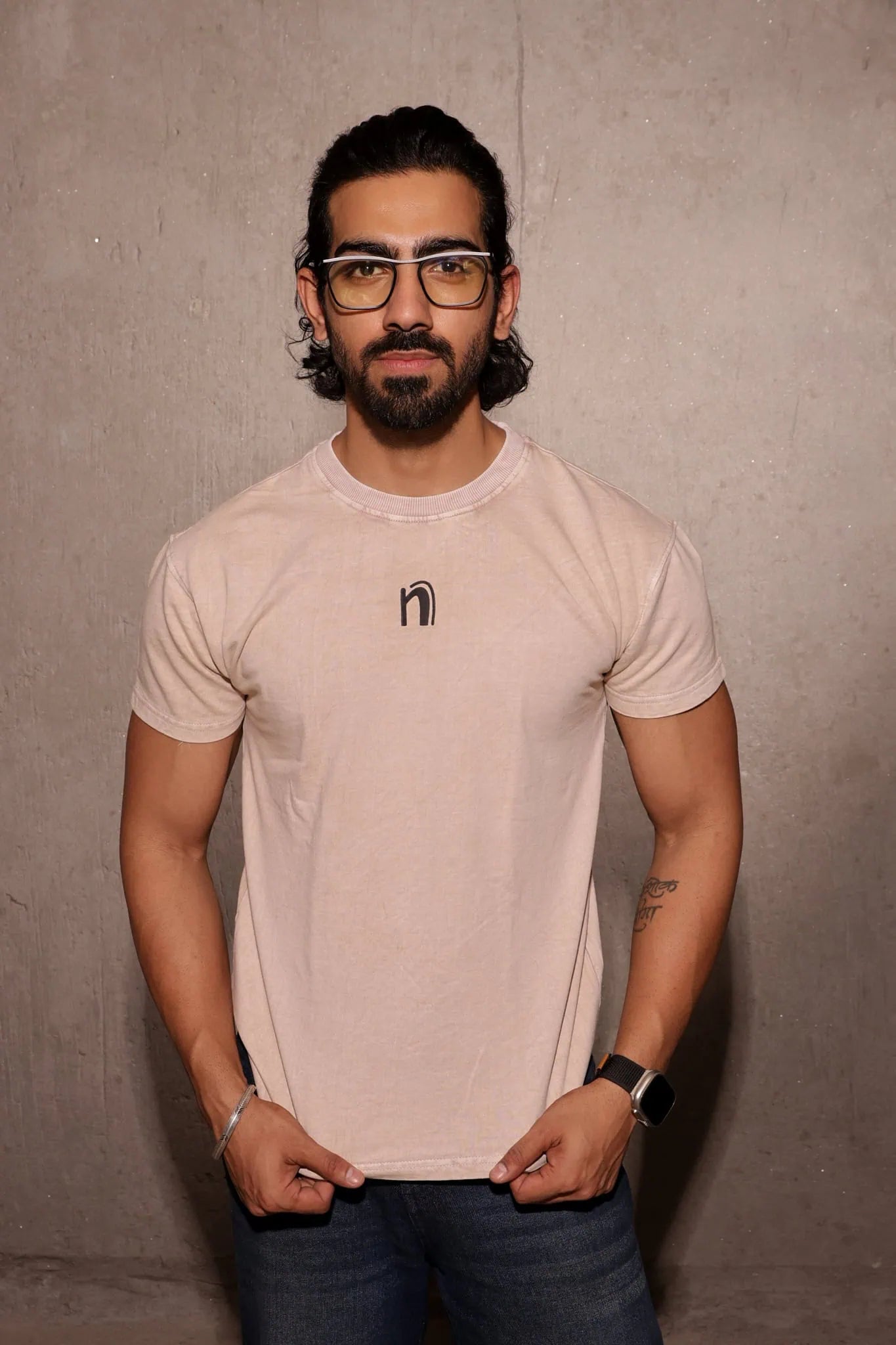Man wearing glasses and a light-colored t-shirt against a plain background