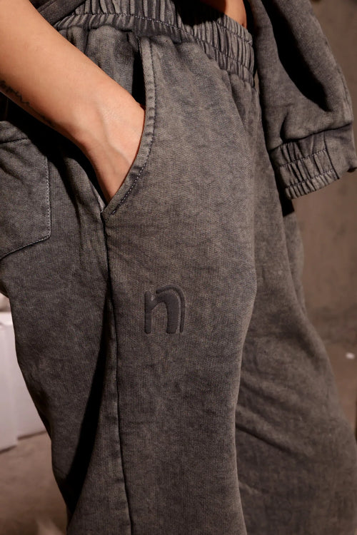 Gray sweatpants with a logo on the pocket against a neutral background