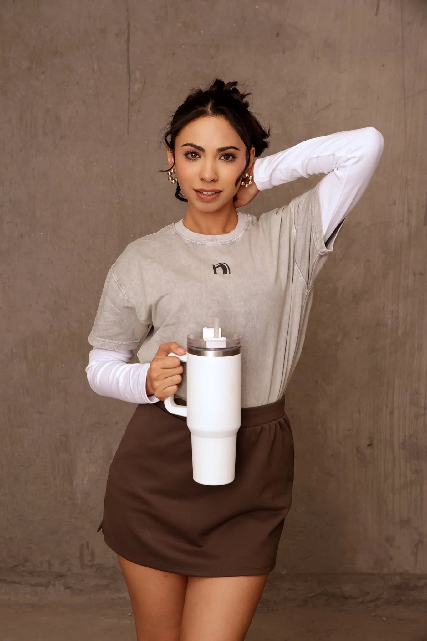 Woman holding a white mug against a brown background