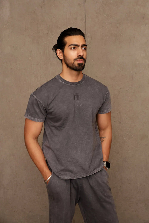 Man wearing a gray t-shirt and pants against a brown background