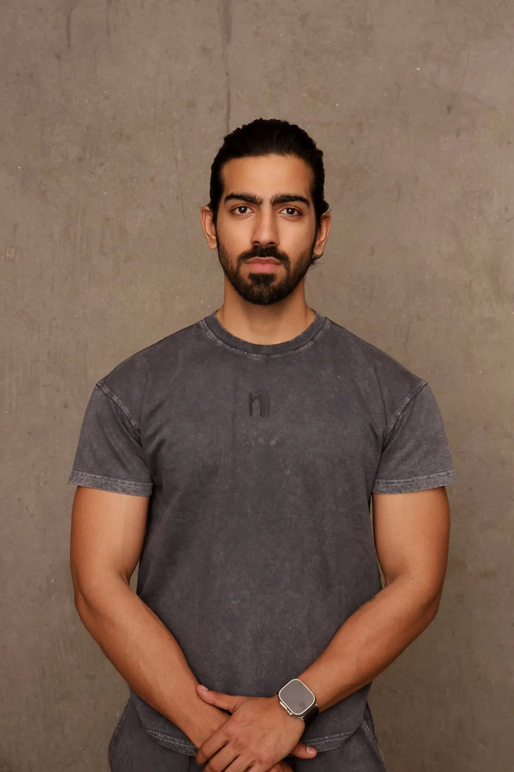 Man wearing a gray t-shirt against a brown background