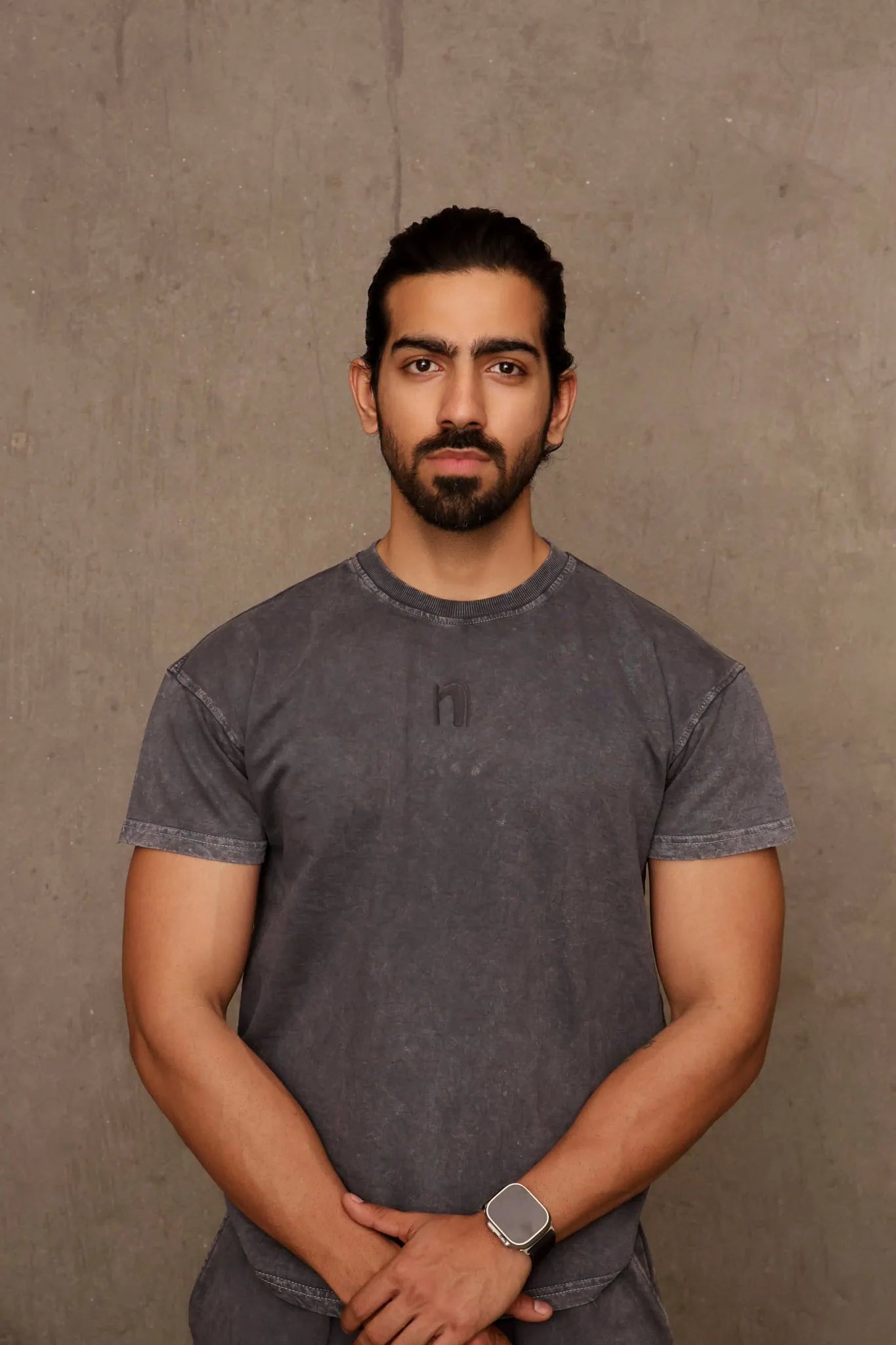 Man wearing a gray t-shirt against a brown background